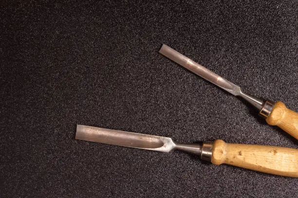 two wooden-handle chisel on a black speckled background top view