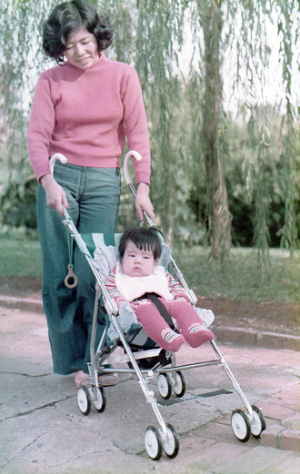 Young mother with her son in baby carriage. This is a digitized old family picture