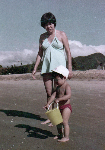 Young mother with her baby son on the beach. This is a digitized old family picture