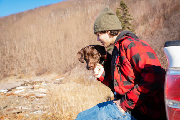 A portrait of a teenaged male with his chocolate Labrador dog