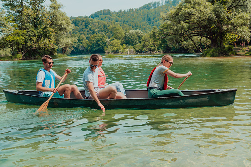 Group adventurous explorer friends are canoeing in a wild river.