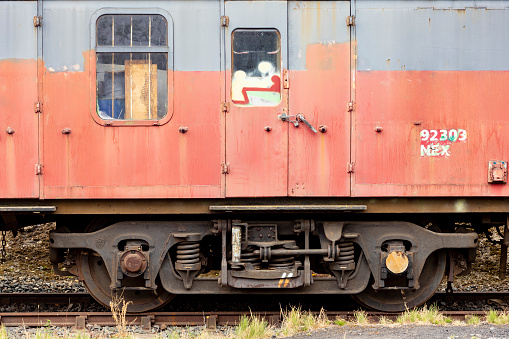 An old passenger railway car with peeling paint on the carriage of the railway.