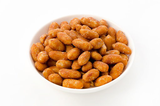 Honey roasted peanuts in white bowl on white background