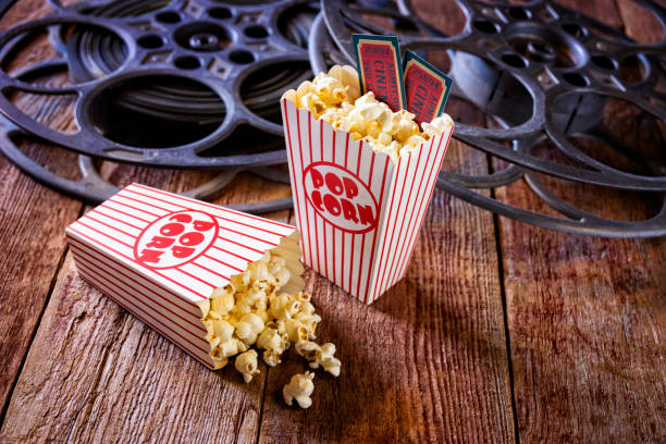 Bags of Popcorn with Tickets and Movie Reels on Retro Wood Background stock photo