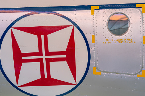 side part of a military plane with a door on the right and a symbol of the Portuguese air force on the left.