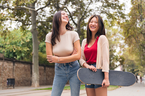 two young women laughing happy and smiling looking at camera, concept of female friendship and teenager lifestyle, copy space for text