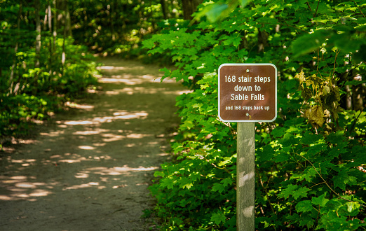 Funny Sign for distance to Sable falls attraction on woods trail head Northern Michigan park