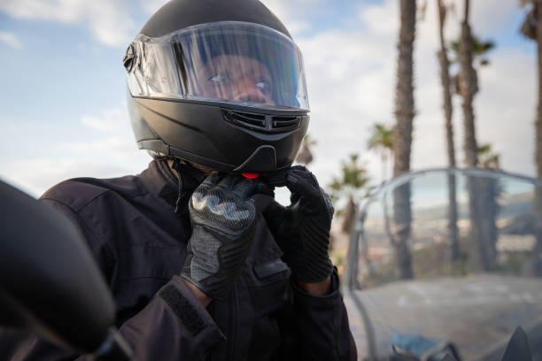 An African biker wears a helmet while sitting on his motorcycle, road safety.