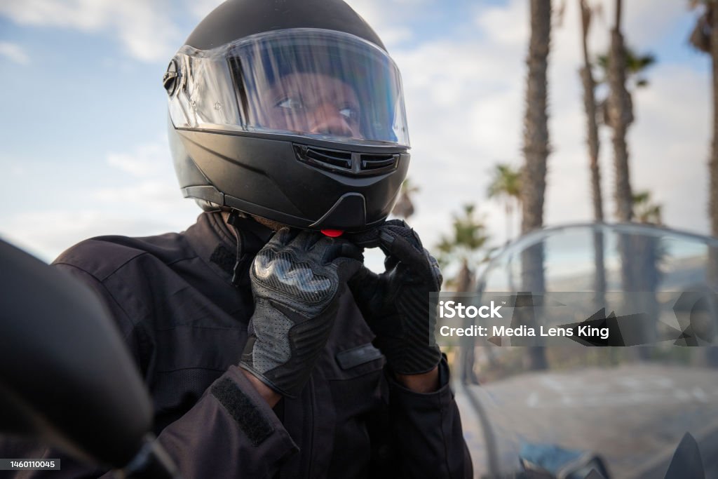 An African biker wears a helmet while sitting on his motorcycle, road safety. An African biker wears a helmet while sitting on his motorcycle, road safety Biker Stock Photo