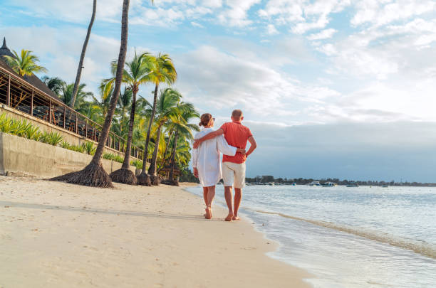 istock Couple in love hugging while walking on a sandy exotic beach. They have an evening walk by Trou-aux-Biches seashore on Mauritius island. People relationship and tropic honeymoon vacations concept 1460117111