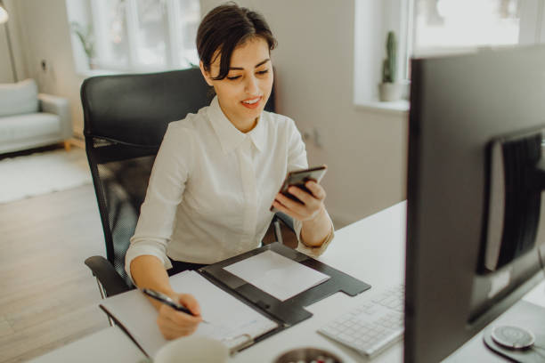 istock Happy businesswoman working while holding her phone 1460117368
