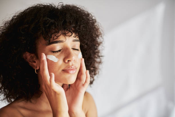 Cream, moisturizer and facial black woman in skincare, beauty or cosmetics promotion on white wall background. Face, calm and gen z people or model lotion, essential oil or moisturizer for skin care crema, crema hidratante y facial negra para mujer en promoción de cuidado de la piel, belleza o cosmética sobre fondo de pared blanca. cara, calma y gen z personas o modelo de loción, crema solar o crema hidratante para el cuidado de la piel