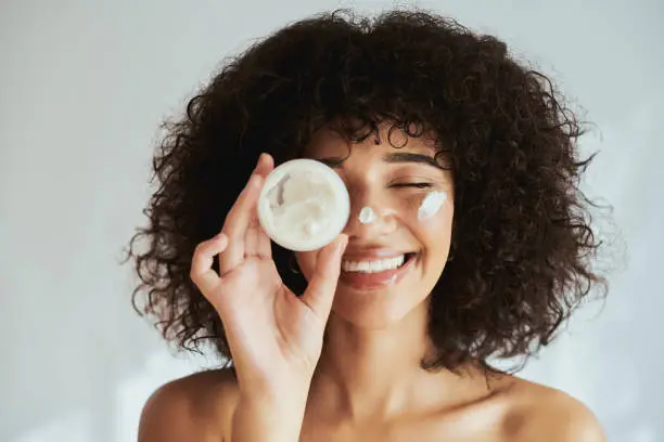 Cream, lotion and face of black woman with beauty product, skincare cosmetics and advertising isolated on white wall. Beautiful skin care person with container, moisturizer and essential oil mockup