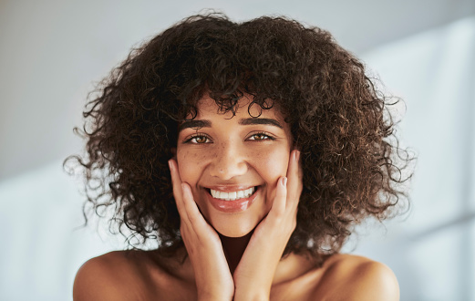 Beauty model, portrait or skincare glow and afro hair, dermatology wellness or healthcare touch in studio or spa. Smile, happy woman or person with hands on face, makeup cosmetics or curly hairstyle