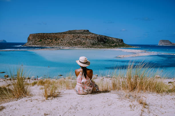 Women at Balos Beach Crete Greece, Balos beach is on of the most beautiful beaches in Greece Balos Beach Crete Greece, Balos beach is one of the most beautiful beaches in Greece on the Greek Island, a woman with a hat looking at ocean crete stock pictures, royalty-free photos & images