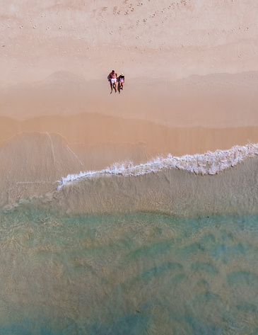 Drone view at a couple walking on the beach of Karon Phuket Thailand during vacation