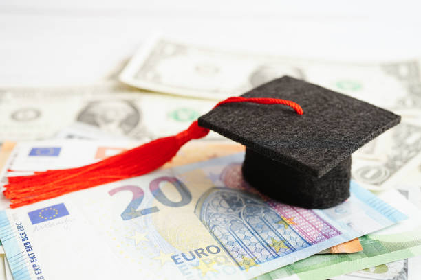 istock Graduation gap hat on Euro and US dollar banknotes money, Education study fee learning teach concept. 1460132483