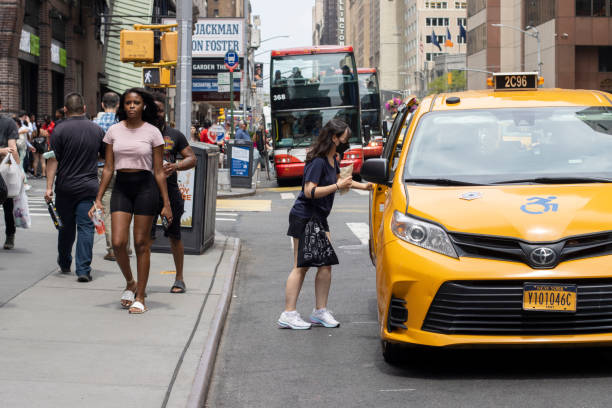 Hailing a Yellow Cab in NYC New York, NY, USA - July 5, 2022: A woman hails a yellow cab in Midtown Manhattan, New York City. new york state license plate stock pictures, royalty-free photos & images