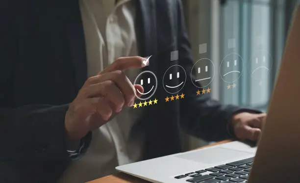 Photo of Selective focus at finger of business man while point finger to choose feedback on excellent customer service with five star score with smile. Service evaluation concept with futuristic icon.