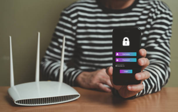 Selective focus at people hand while using smartphone to type password credential to login to Internet wireless connection at home. Network security of internet access into router with futuristic icon enfoque selectivo en la mano de las personas mientras usa el teléfono inteligente para escribir la credencial de contraseña para iniciar sesión en la conexión inalámbrica a internet en casa. seguridad de red de acceso a internet en enrutador con icono