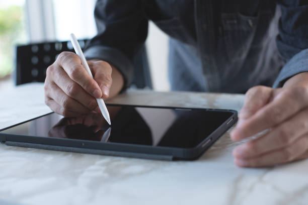 ホームオフィスのテーブルの上の�デジタルタブレットpcでスタイラスペンを使用する男性の手の接写 - digital tablet digitized pen touchpad men ストックフォトと画像