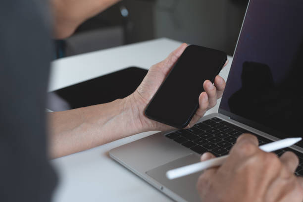 istock Mockup, business man using blank screen mobile smart phone, working on laptop computer at office, template for mobile app design or website advertisement 1460153553