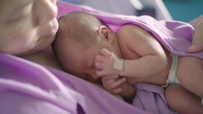 Newborn infant sleeping on mother warmth chest at hospital