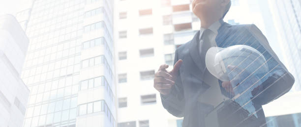istock Double exposure, asian engineer standing at construction site during with skyscraper buildings in the city. The concept of engineering, construction, real estate development, business background 1460160372