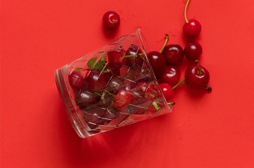 ripe cherries in a glass on a red background