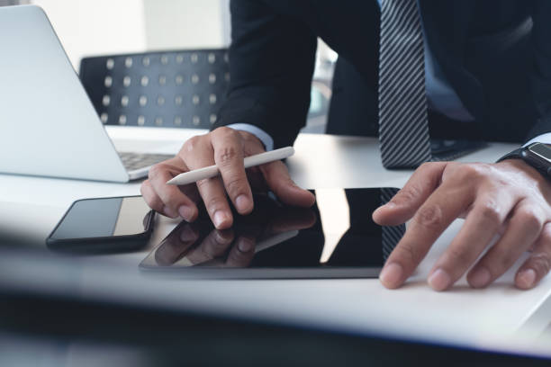 istock Businessman in black suit using digital tablet and  working on laptop computer on table at office. Business man finger touching on tablet screen at desk and suring the internet, close up 1460165030