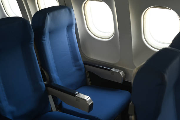 Airplane cabin interior, empty comfortable seats in economy class with portholes. stock photo