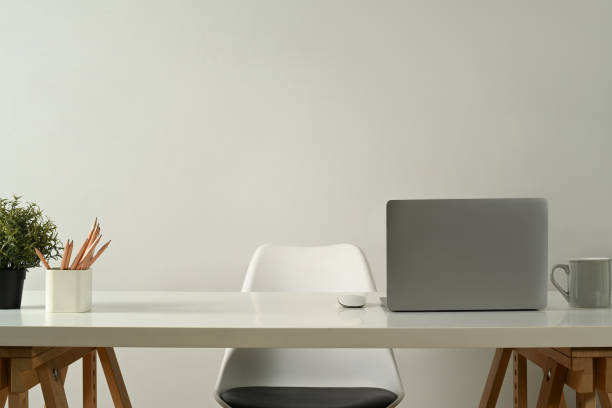 istock Modern home office interior with laptop computer, pencil holder, coffee cup and potted plant on white table. 1460167586