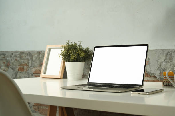 istock Comfortable workplace with laptop computer, smart phone, picture frame and potted plant in white table. 1460167590