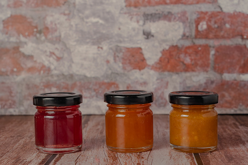 close-up of three jars of jam of different flavors on a wooden table