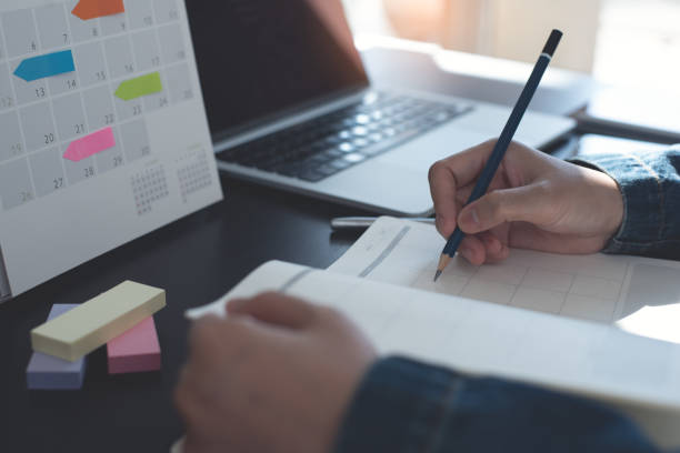 istock Event planner timetable agenda plan on year 2023 schedule event. Business woman checking timetable, taking note on calendar planner notebook on office table. Calendar event plan, work planning 1460168404