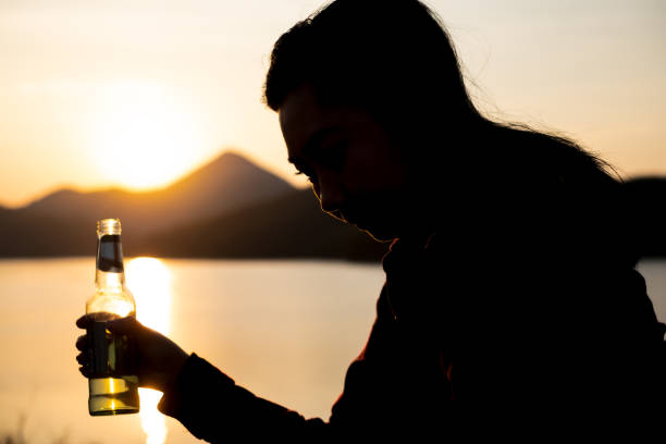 istock Silhouette woman drinking water on the beach at dusk 1460170307