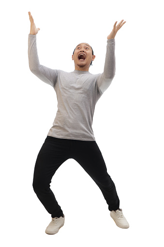 Man wearing casual grey shirt black denim and white shoes, excited surprised shocked and happy anticipating something amazing from above. Full body portrait isolated cut out
