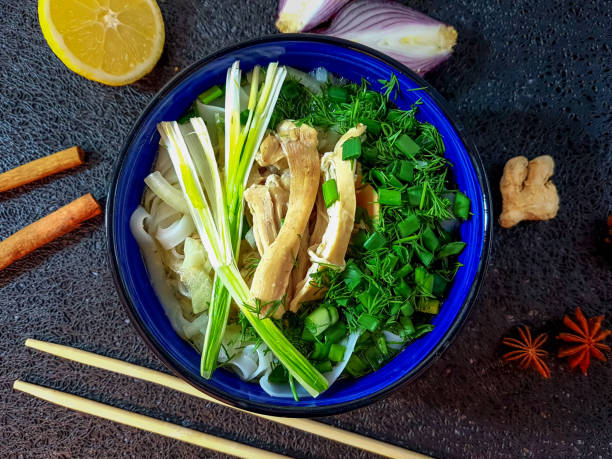 Traditional Pho Bo soup with beef, rice noodles, ginger, lemon in a bowl on a dark background. Vietnamese and Asian cuisine.