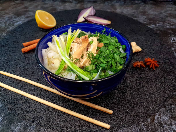 Traditional Pho Bo soup with beef, rice noodles, ginger, lemon in a bowl on a dark background. Vietnamese and Asian cuisine.
