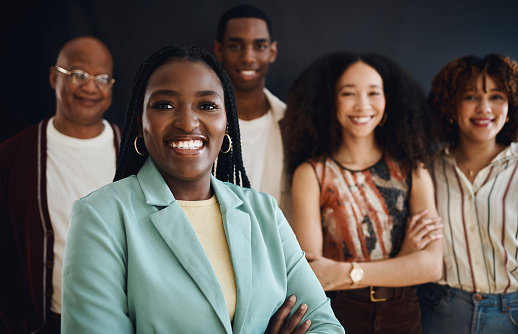 Portrait, teamwork or leadership with a business black woman manager standing arms crossed with her team in a studio. Collaboration, management or trust with a female leader and her employee group