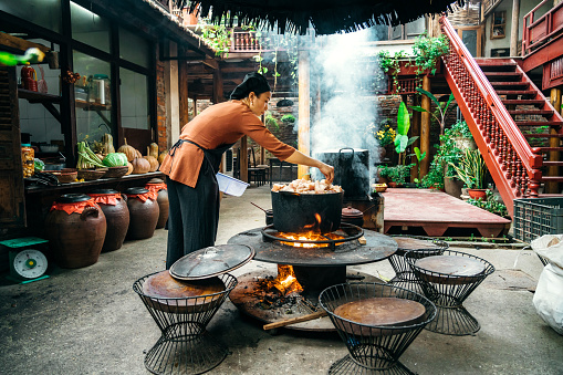 young vietnamese woman is cooking on open fire in restaurant in north vietnam