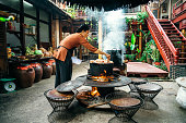 young vietnamese woman cooking steamed fish on open fire in restaurant