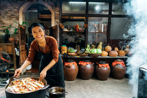 istock smiling vietnamese woman cooking steamed fish on open fire in restaurant 1460180120