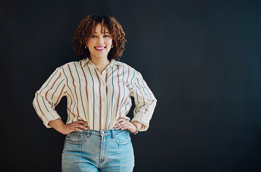 Happy, portrait and woman with an afro in a studio with a casual, beautiful and stylish outfit. Young, beauty and female with natural hair from Mexico with positive mindset posing by black background