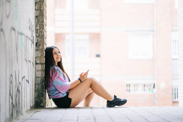 istock Cheerful young Caucasian lady sitting outdoors using her smartphone 1460185619