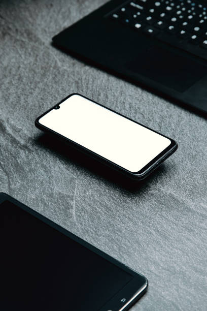 istock Stylized clean office working desk with smartphones and laptop on a gray table 1460189151