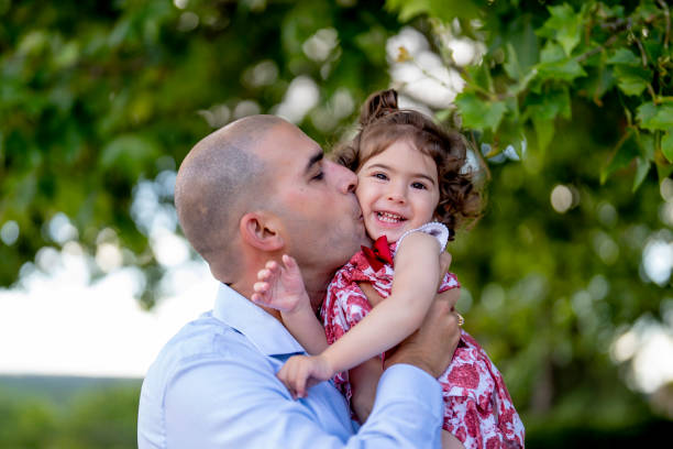 istock Father hugging and kissing her little daughter while walking in a park 1460189460