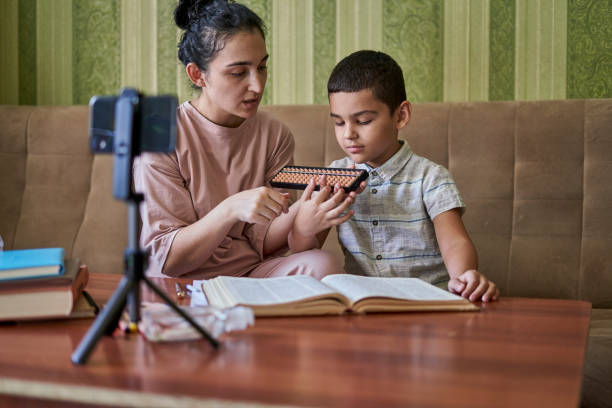 istock Young female teacher explaining the math lesson with a young pupil during an online class 1460190396