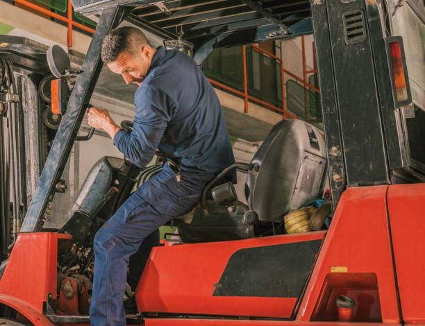 istock Young Latino male getting off an orange forklift in the workshop 1460190933