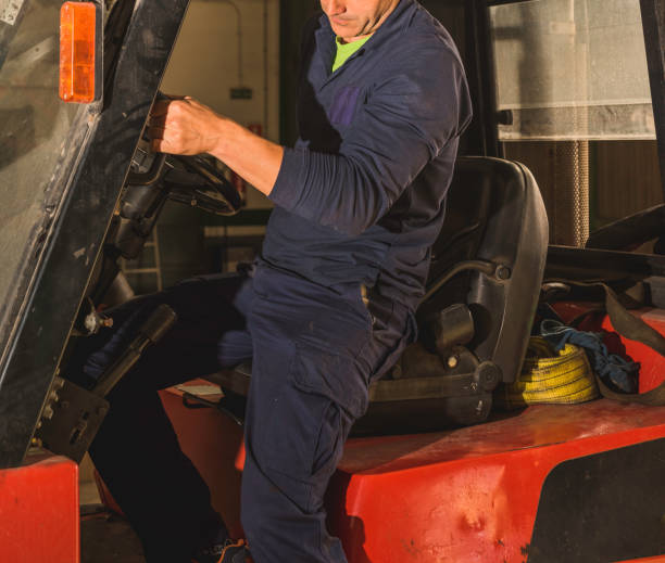 istock Male in dark blue clothes getting off an orange forklift in the workshop 1460190969